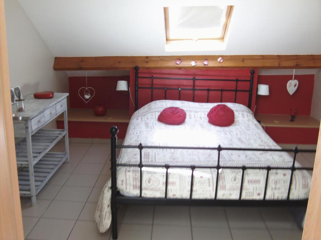 a bedroom with a bed with two red pillows on it at Gîtes "Les Framboisiers" in Neufchâteau