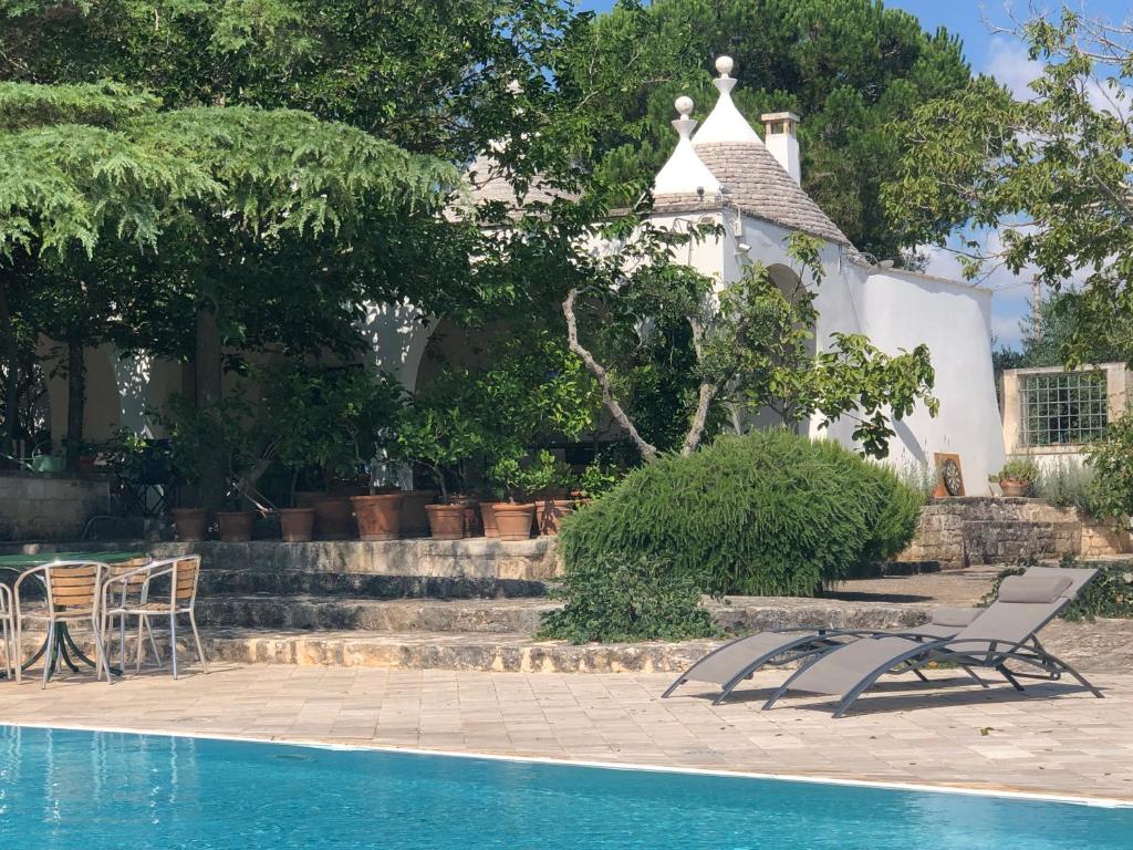 una piscina con sedie e una casa sullo sfondo di I Trulli della NaturaBio a Martina Franca