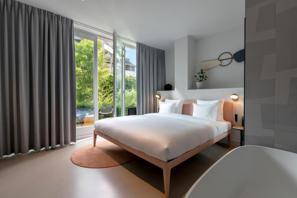 a hotel room with a large bed and a large window at Conscious Hotel Museum Square in Amsterdam