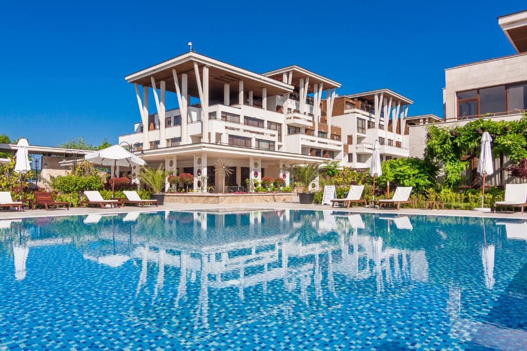 a resort with a swimming pool in front of a building at Apolonia Resort in Sozopol