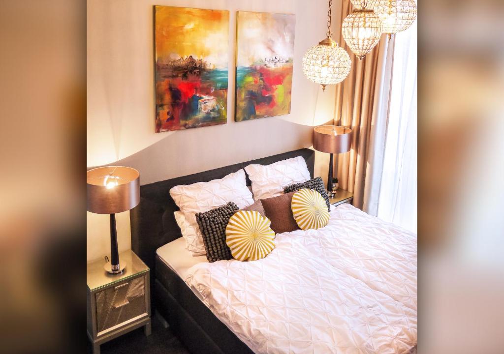 a bedroom with a bed with pillows and paintings at Comfort and Style in City Center with Ensuite Bathroom on Schaafenstraße in Cologne