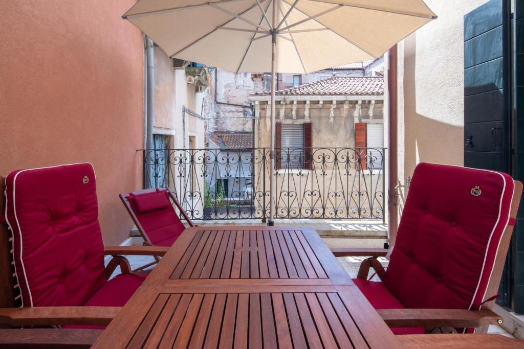 ヴェネツィアにあるVe.N.I.Ce Cera Remer Suiteの木製テーブル、バルコニー(椅子、パラソル付)