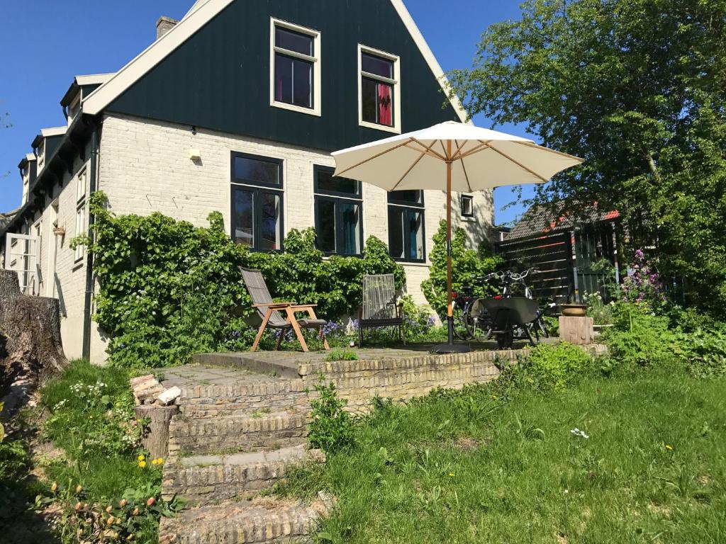 ein Haus mit einem Regenschirm und einem Stuhl im Hof in der Unterkunft Pastorie De Waal in De Waal