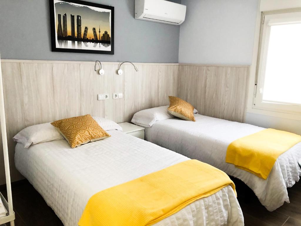 a room with two beds with yellow sheets at Alojamiento HC in Colmenar Viejo