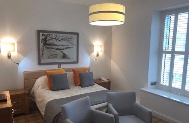 a bedroom with a bed and two chairs and a lamp at The Commodore Hotel in Instow