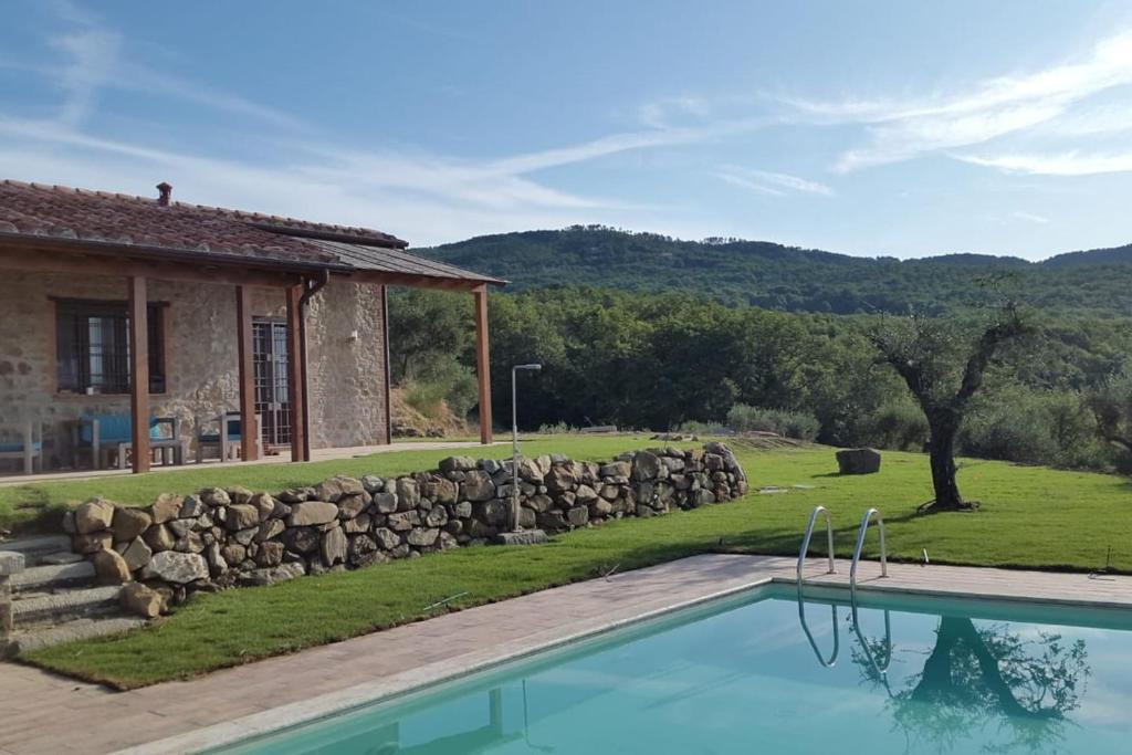 una casa con piscina junto a una pared de piedra en Di Colle In Colle - Country House with Private Pool, en Tuoro sul Trasimeno