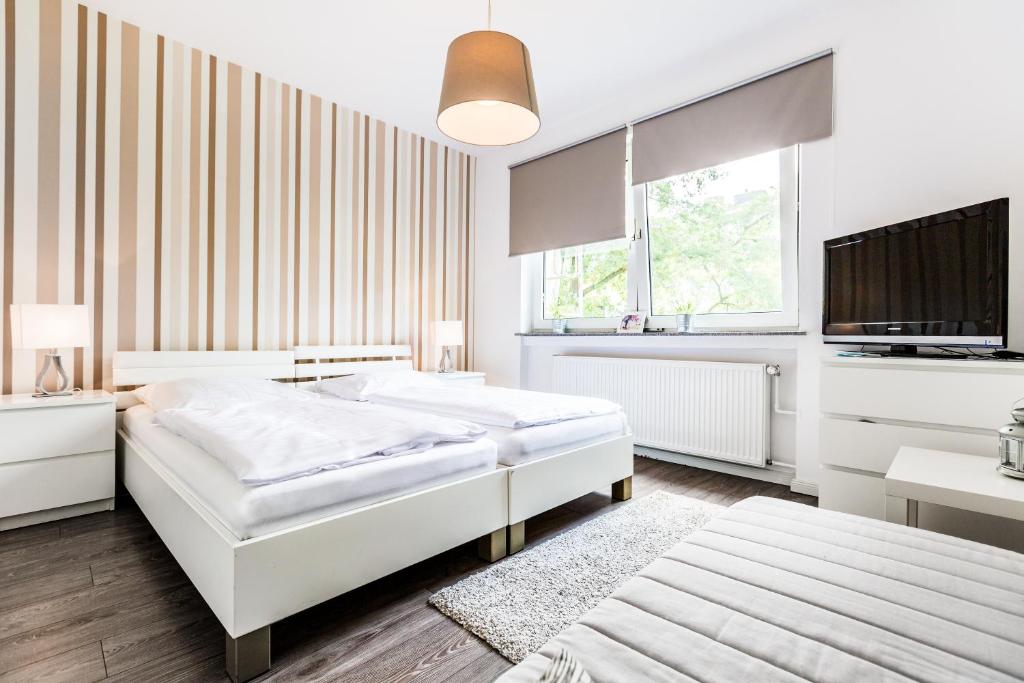 ケルンにあるApartments Kölnの白いベッドルーム(ベッド2台、テレビ付)
