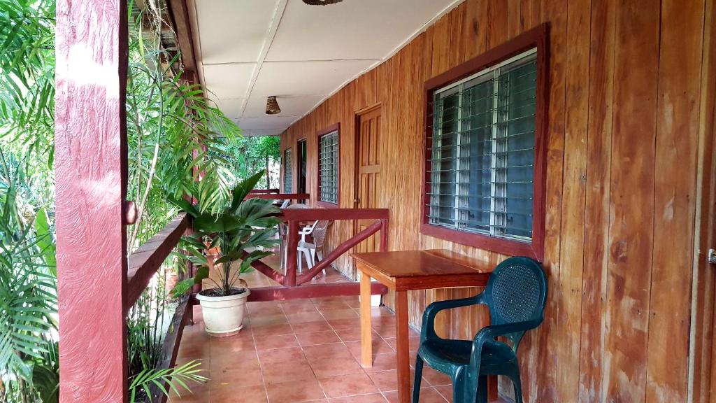 eine Holzterrasse mit einem Holztisch und einem Stuhl in der Unterkunft Guest house Posada Ixchel in El Remate