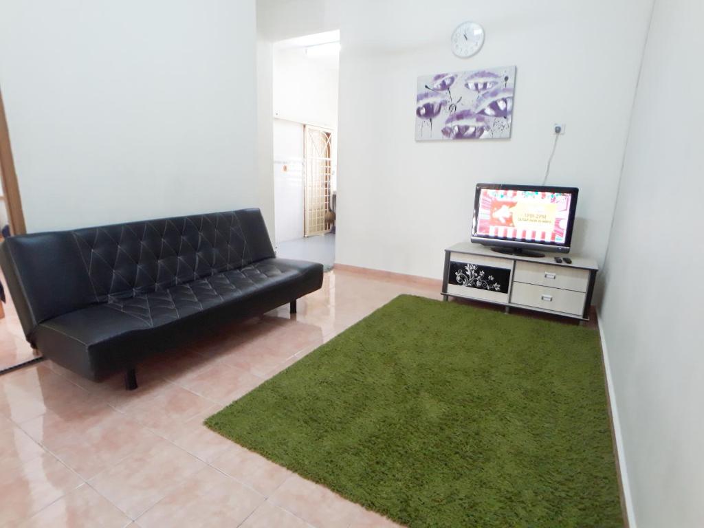 un sofá de cuero negro en una sala de estar con TV en JJ Melaka Holiday home, en Melaka