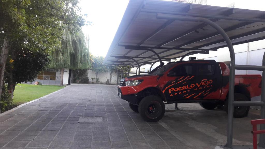 un camión rojo está estacionado bajo un toldo en Apart Hotel Pueblo Viejo en San Juan