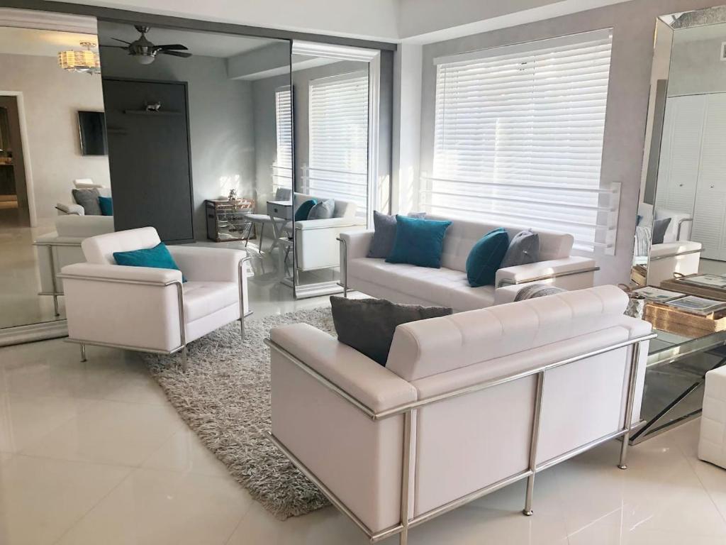 a living room with white couches and blue pillows at Heart of South Beach / Modern Apartment / Ocean Drive - Carlyle in Miami Beach