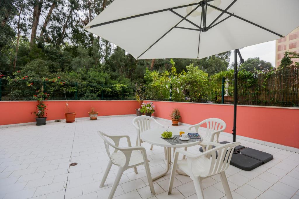 Un patio con una mesa y sillas blancas y una sombrilla. en Like-home-T4-Bright Benfica Apt-Terrace, en Lisboa