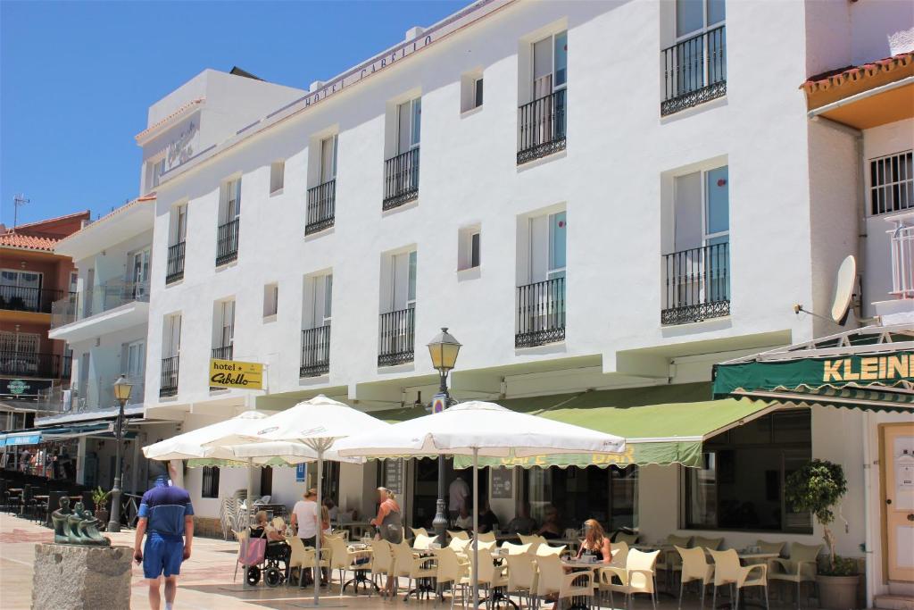 een groot wit gebouw met tafels en parasols ervoor bij Hotel Cabello in Torremolinos