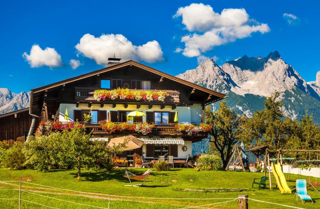 a house with flowers in front of mountains at Oberstockinghof in Saalfelden am Steinernen Meer