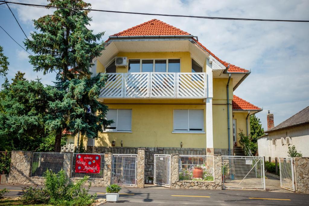 Virágos vendégház في كيزتيلي: منزل اصفر بسقف احمر