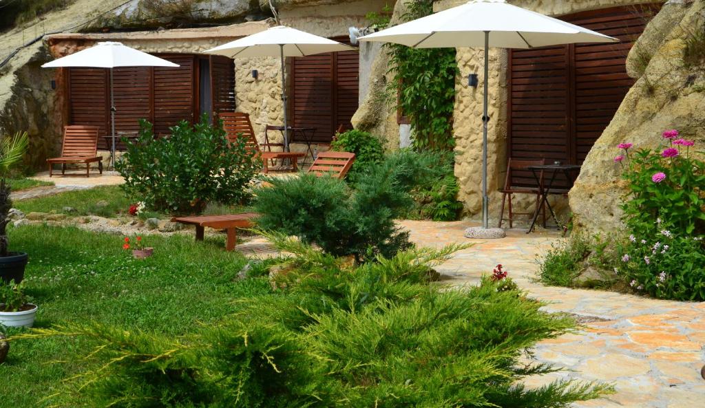 a patio with chairs and umbrellas in a garden at Sirocave barlang apartmanok in Sirok