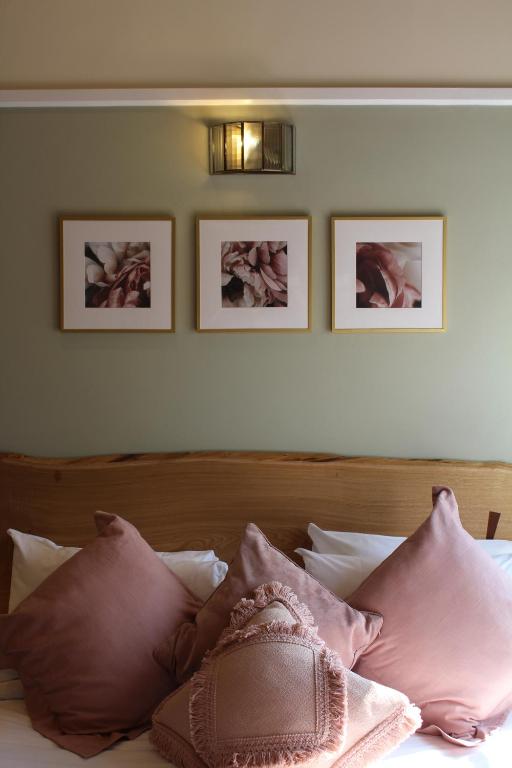 1 cama con almohadas rosas y cuadros en la pared en The Nags Head Hotel en Great Missenden