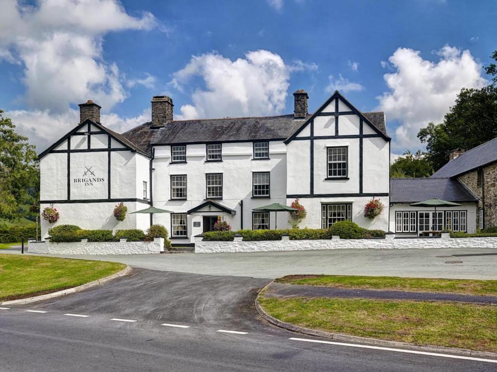 a white and black house on a road at Brigands Inn in Mallwyd