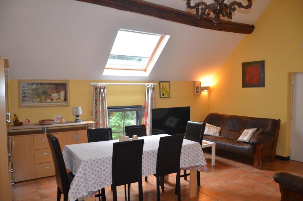 a kitchen and living room with a table and chairs at Le Gîte de la Gentilhommière du Château de Ragnies. in Lyrée