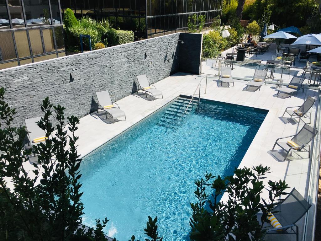 uma piscina com espreguiçadeiras e uma piscina em Golden Tulip Aix en Provence em Aix-en-Provence