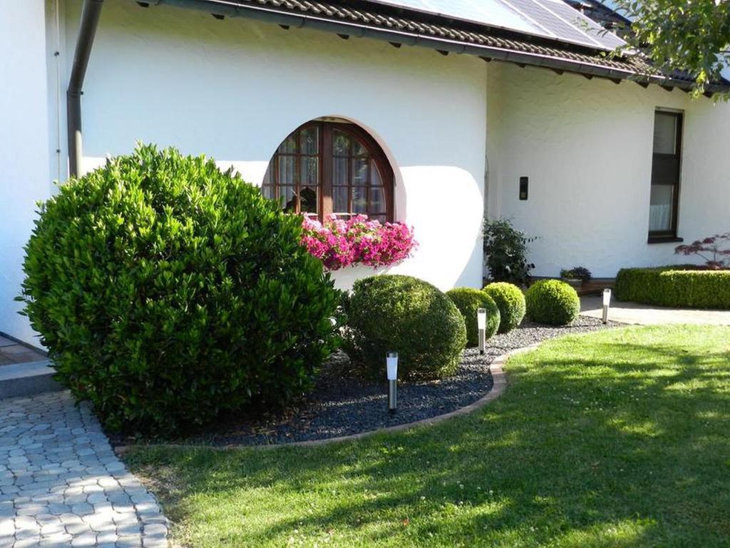 einen Garten mit Büschen und ein Haus mit Fenster in der Unterkunft Ferienwohnung Schwendemann in Laichingen