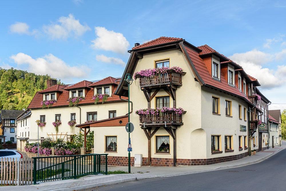 a large house with flowers on the balconies on a street at Pension Zur Grünen Eiche in Kaulsdorf
