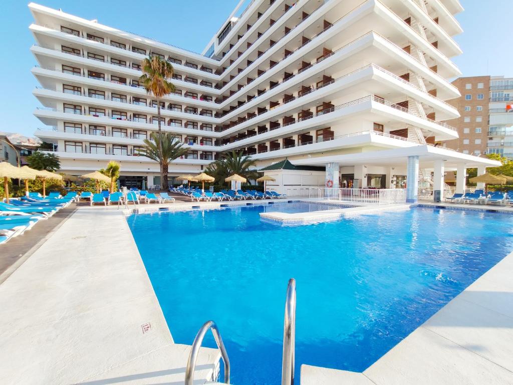 a swimming pool with chairs and a large building at BLUESEA Gran Cervantes in Torremolinos