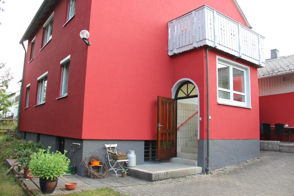 a red building with a door and a balcony at Ferienhaus Betty in Selbitz