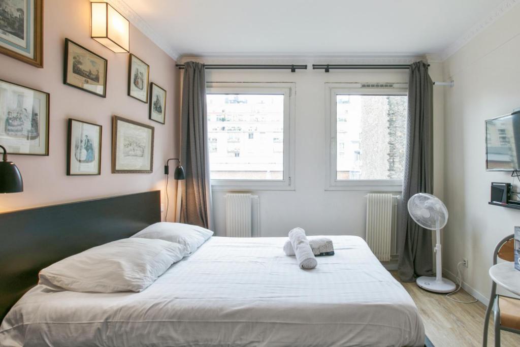 Schlafzimmer mit einem Bett mit weißer Bettwäsche und einem Fenster in der Unterkunft Cozy studio 10 min from Eiffel Tower Invalides Beaugrenelle in Paris