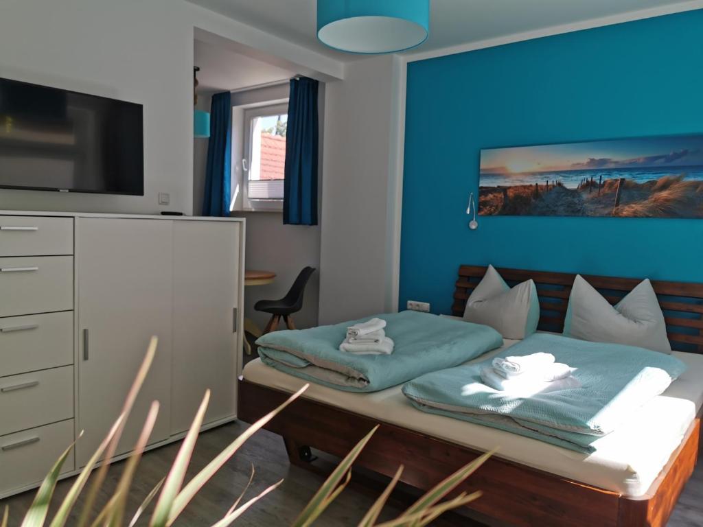 a bedroom with a bed with a blue wall at Gästehaus Twee Linden in Warnemünde