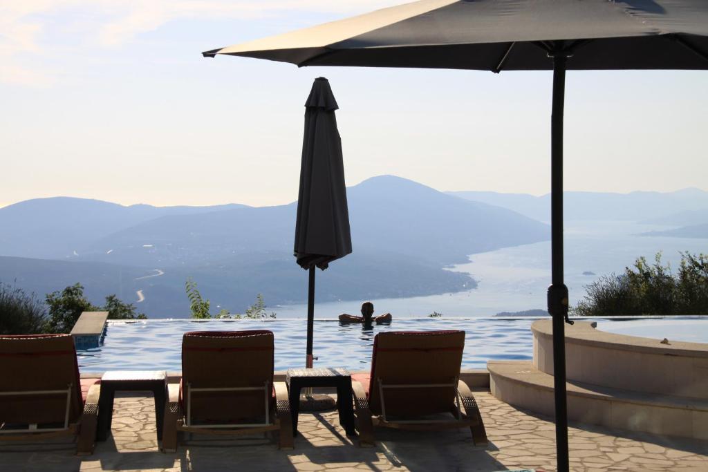 un grupo de sillas y una sombrilla junto a la piscina en Villa Eagle Eye Montenegro en Kotor