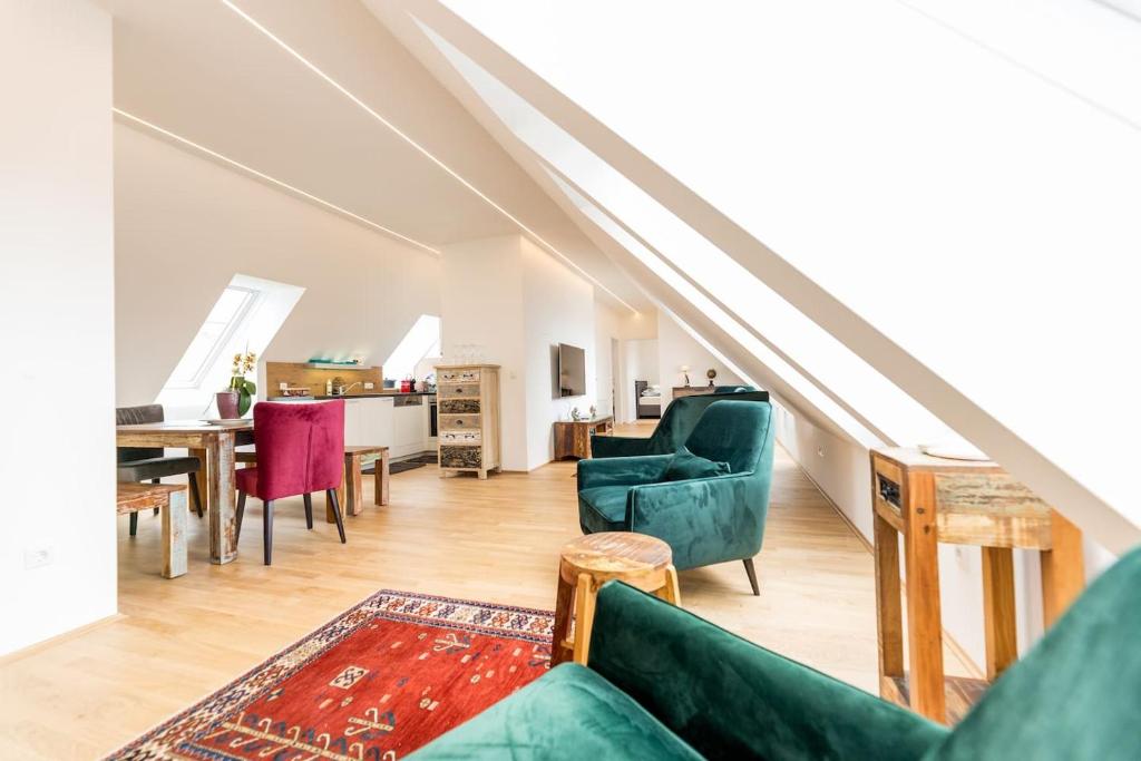 a living room with green furniture and a dining room at Große Dachgeschosswohnung im Herzen von Graz in Graz