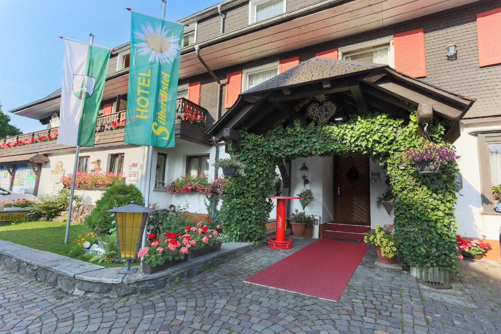 un edificio con una puerta roja y flores delante de él en Hotel Silberdistel en Hinterzarten