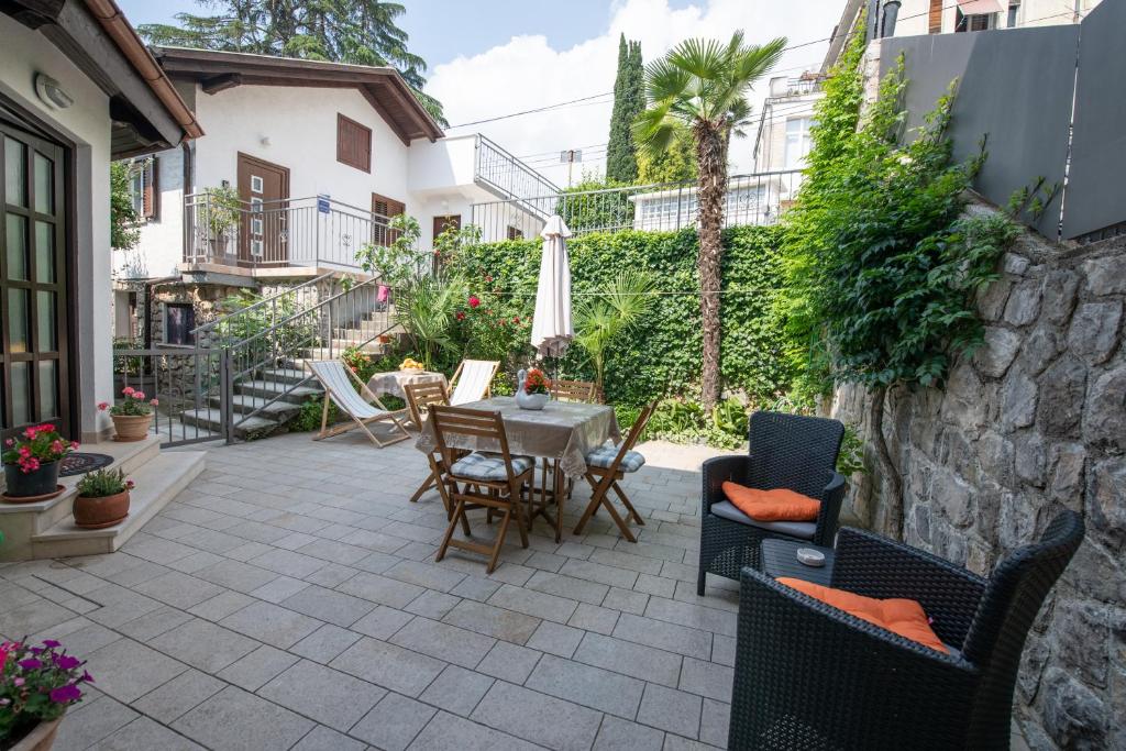 a patio with a table and chairs and a stone wall at Studio apartman Tasha in Opatija