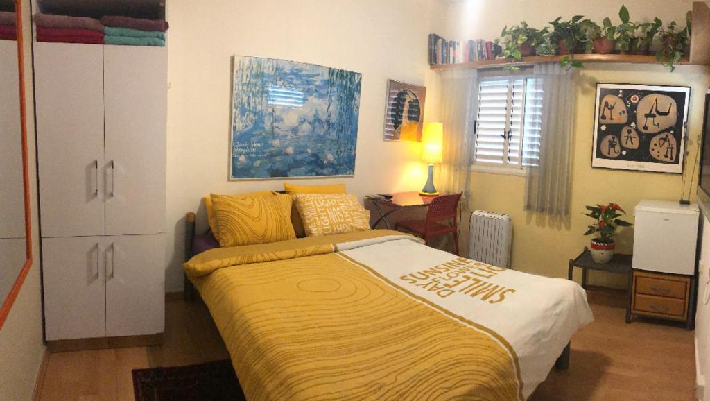 a bedroom with a large bed with a yellow blanket at Comfortable quiet room with a private bathroom in shared apartment in Tel Aviv