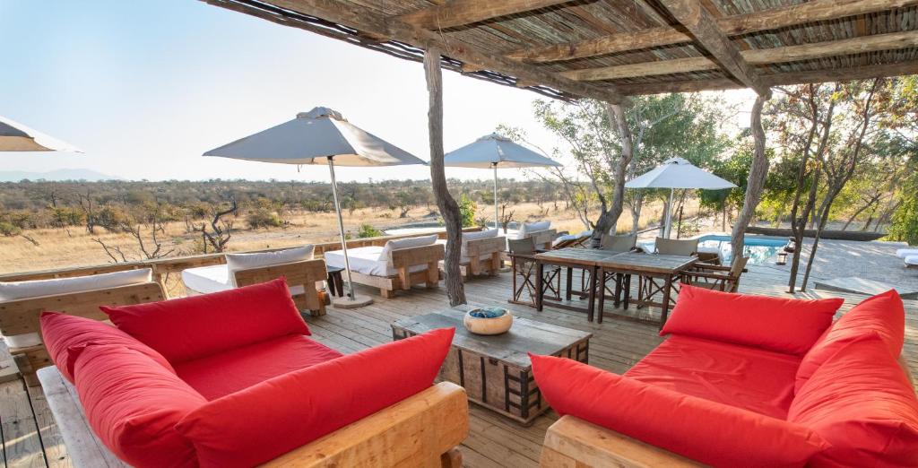 un patio con almohadas rojas, mesas y sombrillas en Baobab Ridge, en Reserva Natural de Klaserie