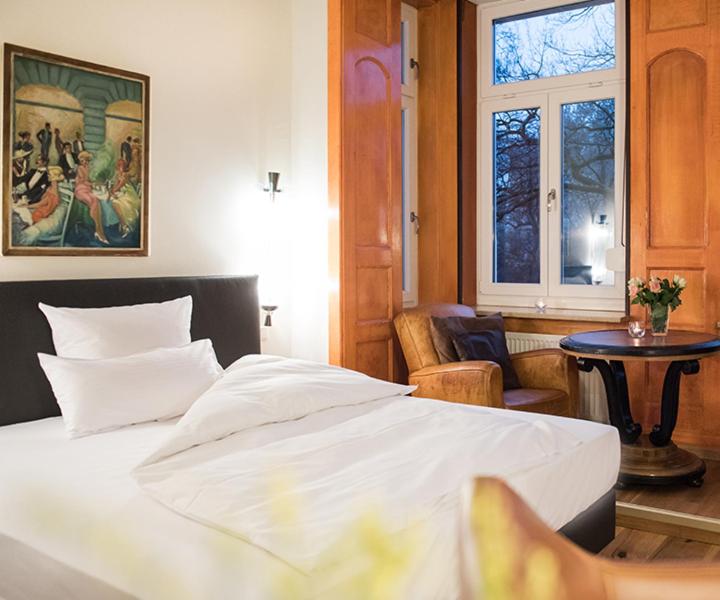 Schlafzimmer mit einem Bett, einem Tisch und einem Fenster in der Unterkunft Hotel Ritzi in München