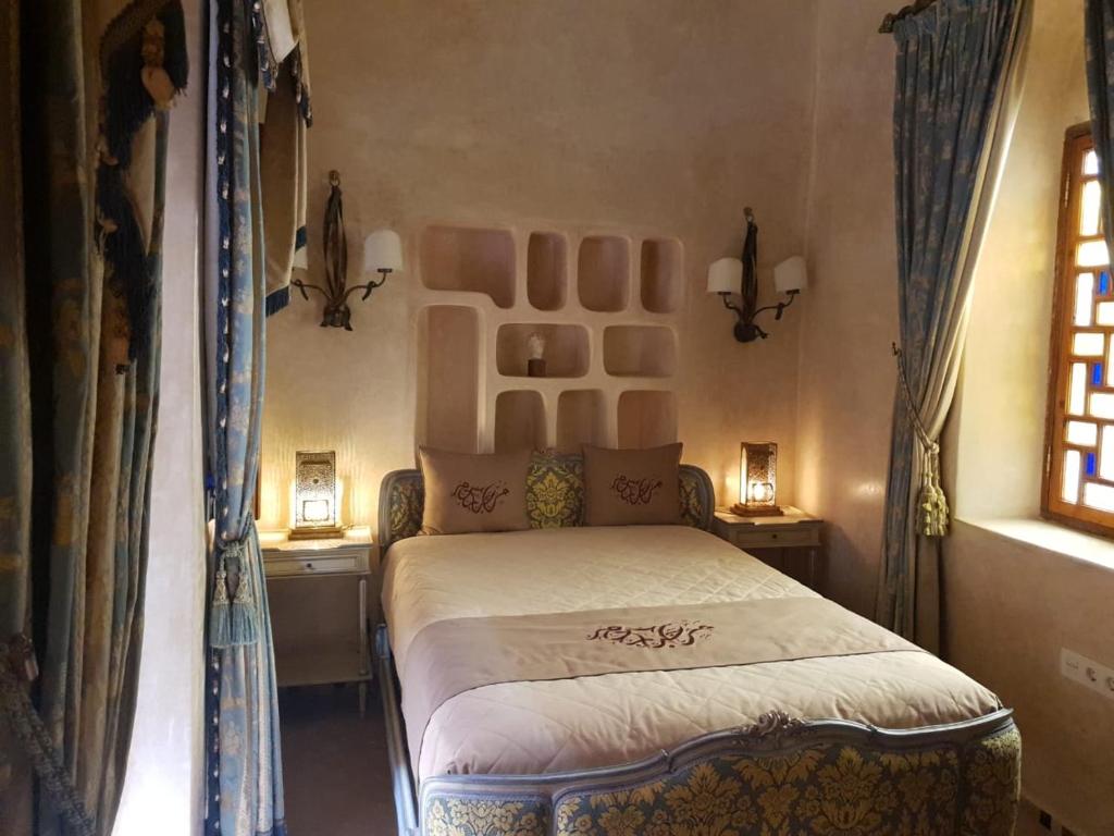 a bedroom with a bed and two tables and a window at Sultana larache in Larache