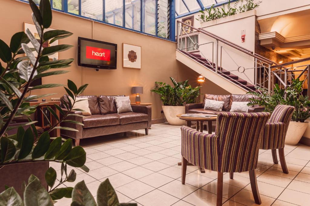 a lobby with couches and a tv and plants at The Gardens Hotel in Manchester