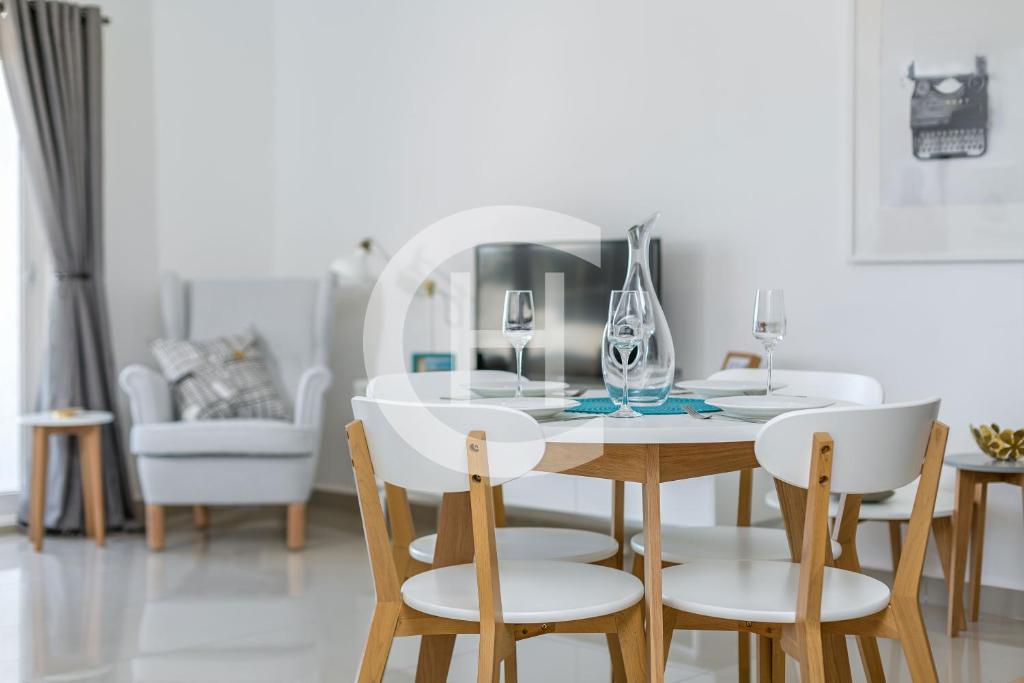 a white dining room with a table and chairs at The Gallery by Clifton Homes in Accra