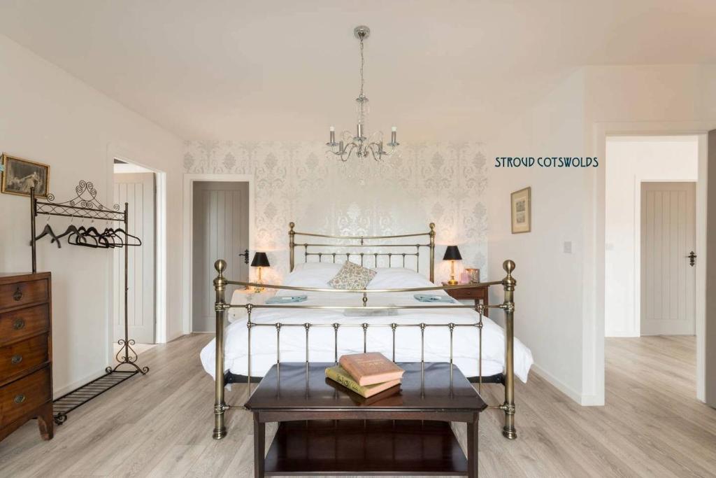 1 dormitorio con 1 cama con mesa y lámpara de araña en The Hidden House, en Stroud