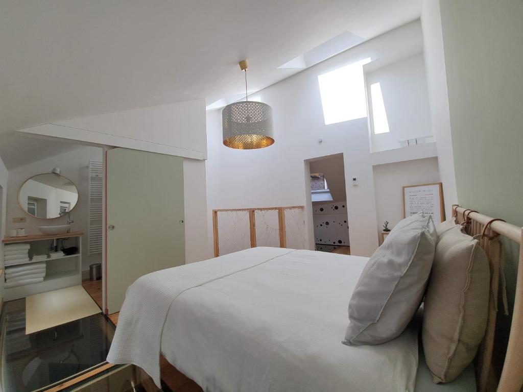 Bel appartement au cœur de Liège في لييج: غرفة نوم بسرير ابيض ومرآة