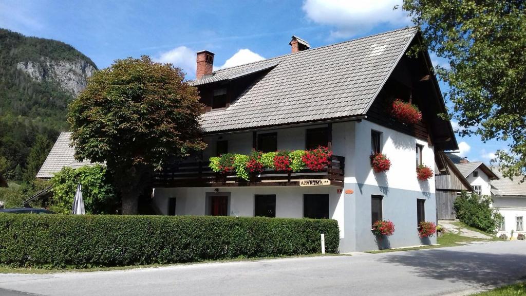a white house with flower boxes on the balcony at Apartma Pr Gatej in Bohinj