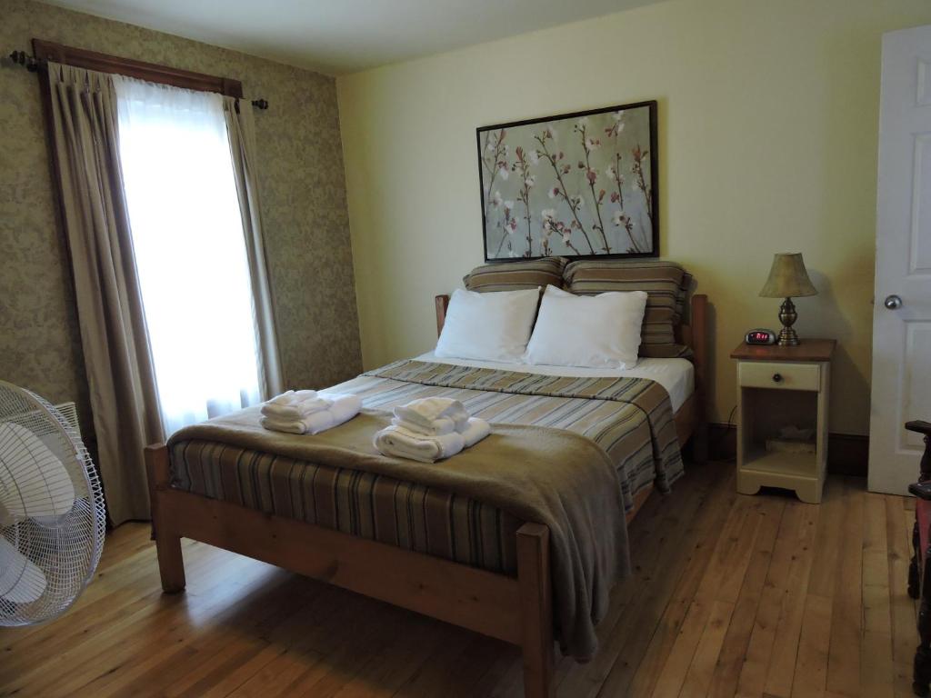 1 dormitorio con 1 cama con 2 toallas en Auberge Ayer's Cliff, en Ayers Cliff
