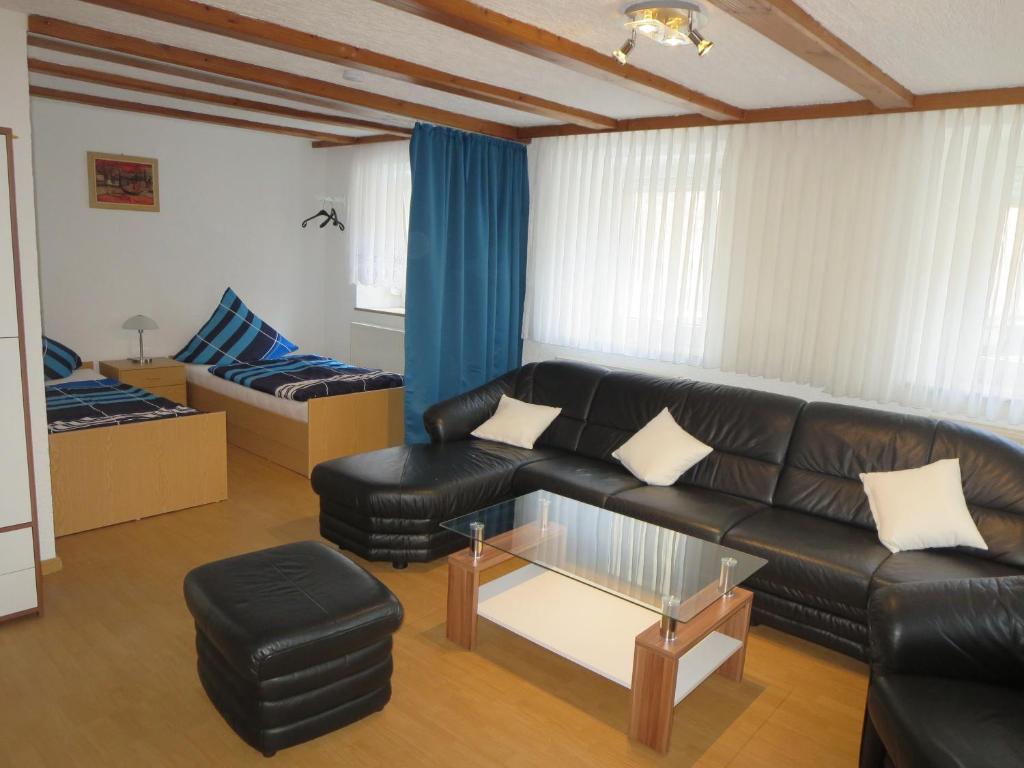 ein Wohnzimmer mit einem schwarzen Ledersofa und einem Tisch in der Unterkunft Ferienwohnung Schloßberg in Pretzfeld