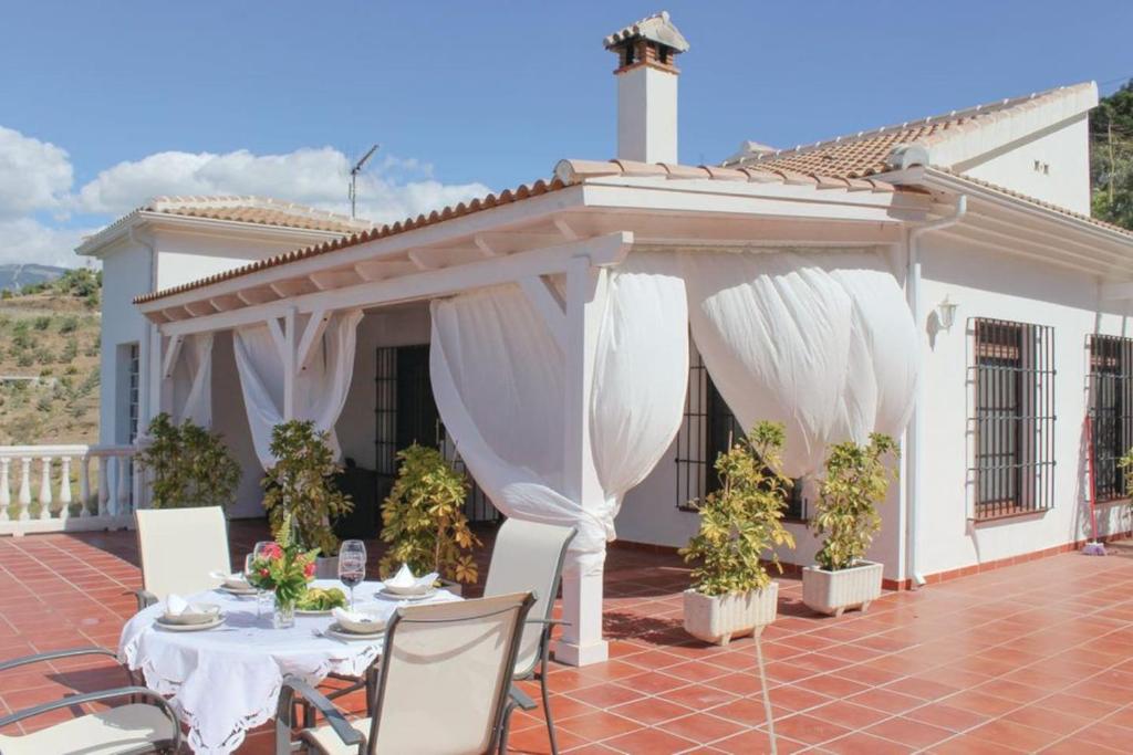 eine Terrasse mit weißen Vorhängen auf einem Haus in der Unterkunft Fuentezuelas Pool Villa in Sayalonga