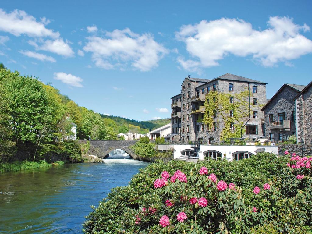 un río en una ciudad con un puente y flores en Whitewater Hotel & Spa en Newby Bridge