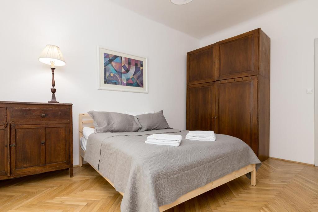 een slaapkamer met een bed en een houten kast bij Powiśle Superior Apartment in Warschau