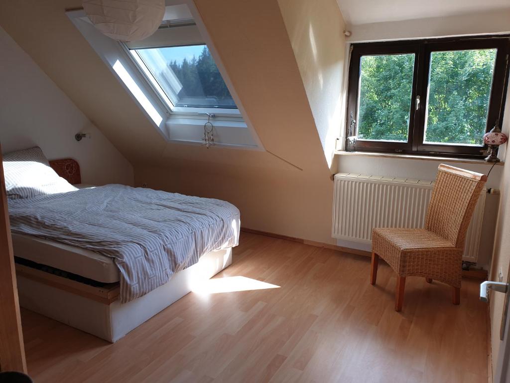 1 dormitorio con cama, ventana y silla en Ferienloft im Grünen, en Gschwend
