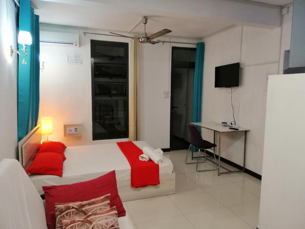 um quarto com uma cama branca e almofadas vermelhas em Residence Les Bambous B&B em Mahébourg